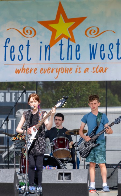 Music- girl rocker with sign Notasium student band playing at Fest in the West